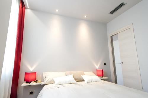 a white bedroom with a bed and two red lamps at Italianflat - Arena di Verona Apartments in Verona