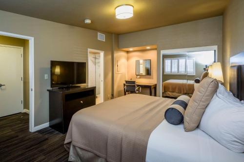 a hotel room with a bed and a flat screen tv at Lions Gate Hotel in Sacramento