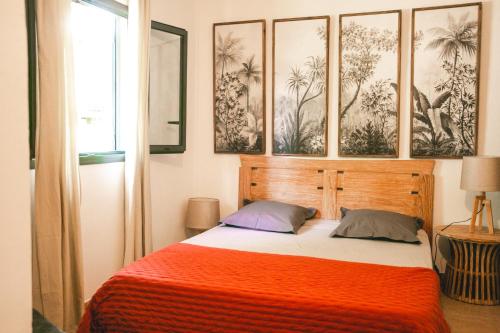 a bedroom with a bed with an orange blanket at Villa Le Colonial Zen - T4 à 5 mn Aéroport in Sainte-Marie