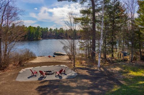 帕里灣的住宿－Perfect 3 bedroom waterfront muskoka cottage，两把红色椅子坐在湖边