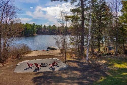 2 chaises rouges assises à côté d'un lac dans l'établissement Perfect 3 bedroom waterfront muskoka cottage, à Parry Sound