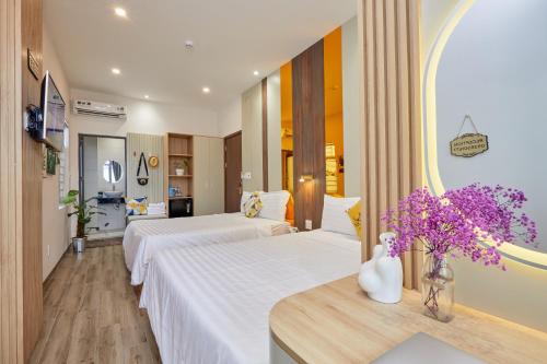 a hotel room with two beds and flowers on a table at Lux Quy Nhon Homestay in Quy Nhon