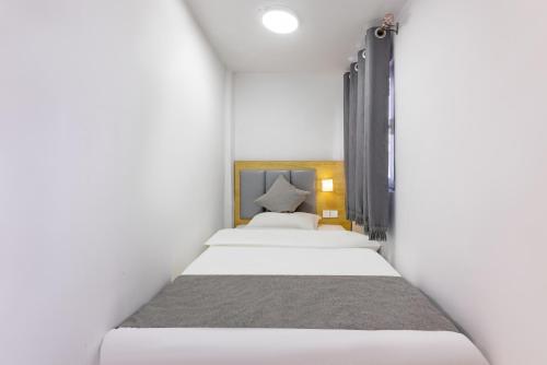 two beds in a small room with white walls at Happy Dragon Hotel -- Nearby Tiananmen square & Forbidden City & Line 5,6,8 Subway Nearby & Free coffee & Free laundry & Fluent English speaking& Tourist attractions ticket service & Free WiFi unlimited for Western software, Shuttle bus to the Great Wall in Beijing