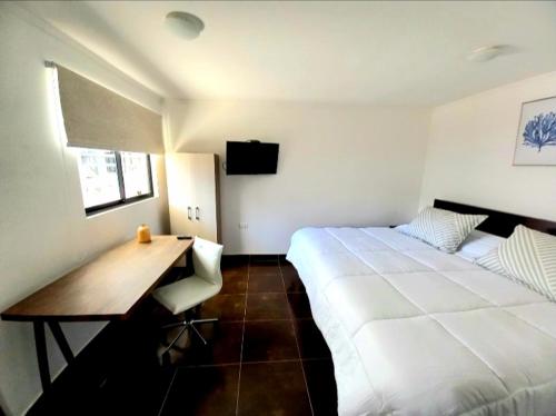 a bedroom with a large white bed and a desk at Hostal Tabancura in Copiapó