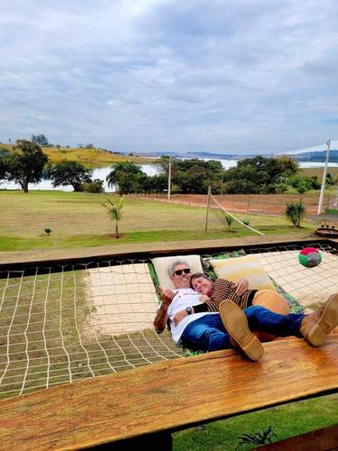 two people laying on a bench in a park at Rancho Recanto da Serra in Delfinópolis
