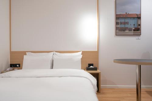 a bedroom with a white bed and a table at Aank Hotel Cheonan Station 1st in Cheonan
