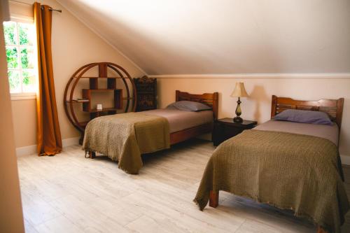 1 dormitorio con 2 camas y espejo en LE COLONIAL, T4 à 5 mn Aeroport dans villa de standing en Sainte-Marie