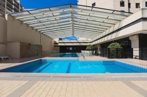 a large swimming pool with awning next to a building at Hotel Aeroporto de Congonhas - Flat in São Paulo