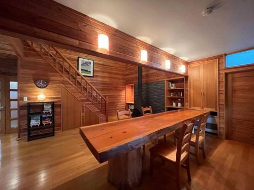 un grande tavolo in legno in una stanza con scala di 貸し別荘 Key of Private Villa 'ムササビハウス' a Kita-karuizawa