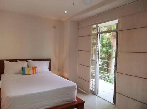 um quarto com uma cama branca e uma porta de vidro deslizante em Apartamento Cali-Granada Piscina em Cali
