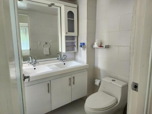 uma casa de banho com um WC, um lavatório e um espelho. em 3 bedroom, front of the beach and pool em Juan Dolio