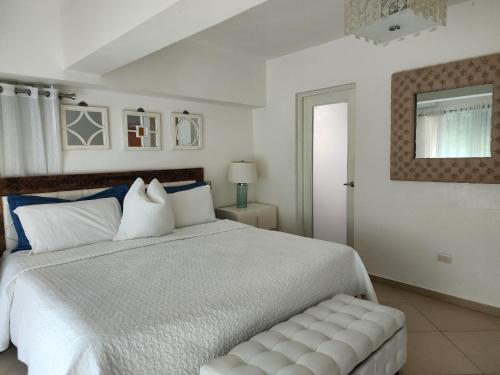 una camera da letto con un grande letto bianco con panca di 3 bedroom, front of the beach and pool a Juan Dolio