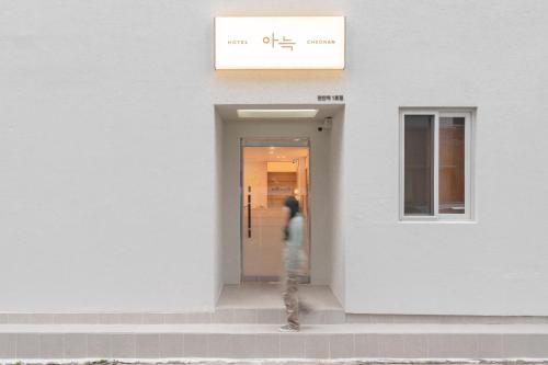 a person standing in the doorway of a white building at Aank Hotel Cheonan Station 1st in Cheonan