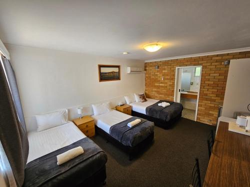 a hotel room with two beds and a couch at Hunter Valley Motel in Cessnock
