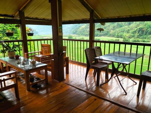 a screened in porch with tables and chairs and a view at Nặm Pé Homestay in Bak Kan