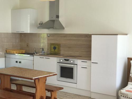 - une cuisine avec des appareils blancs et une table en bois dans l'établissement Maison avec Courette à 450m de la Plage et Proche Commerces - Tout Équipée - FR-1-22-176, à La Tranche-sur-Mer