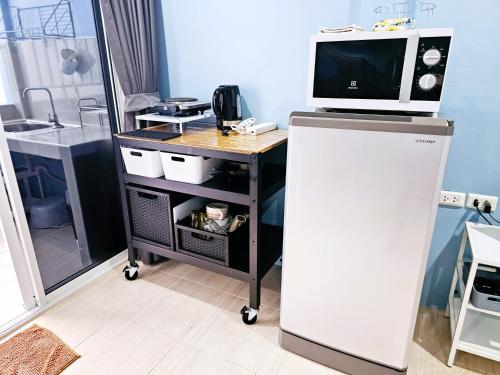 a microwave on top of a cart with a television on it at Near boxing center, 1BR apartment, Sofa bed, Wifi in Chalong 