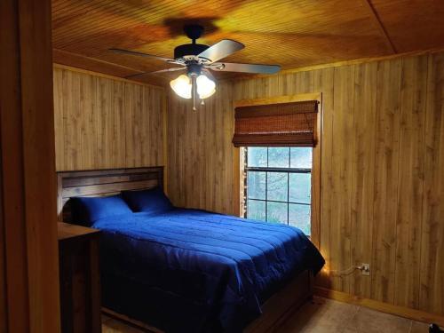 a bedroom with a blue bed and a ceiling fan at Quiet cabin near Enid Lake in Enid