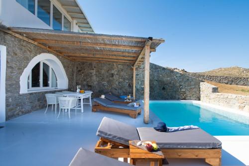 Villa con piscina con mesa y sillas en Amma Houses Sea View, en Kalafatis