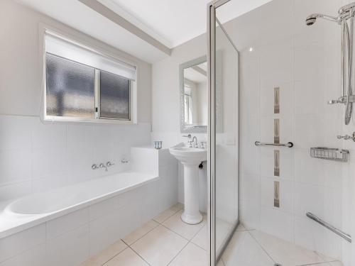 a white bathroom with a sink and a shower at 11 Wills Avenue Golden Beach QLD in Golden Beach