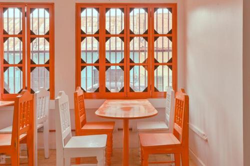 Macarena Hostel في فلوريس: غرفة طعام مع طاولة وكراسي ونوافذ