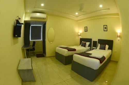 a hotel room with two beds and a mirror at Seasons Stay in Vijayawāda