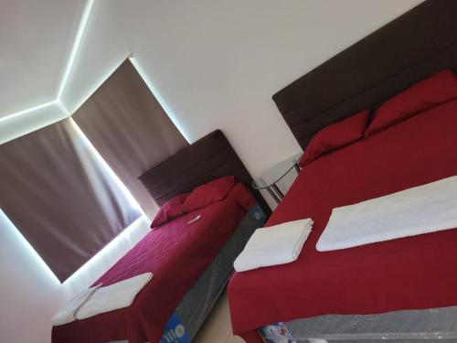 2 camas en una habitación pequeña con sábanas rojas en Casa en condominio monterrico, en Iztapa