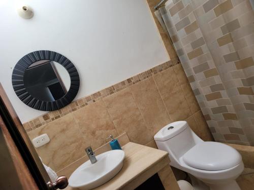 a bathroom with a toilet and a sink and a mirror at Casa en condominio monterrico in Iztapa