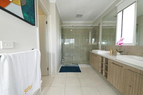 y baño con ducha, lavabo y espejo. en Wyndham 5BR Spacious Holiday Vacation Home WiFi, en Truganina