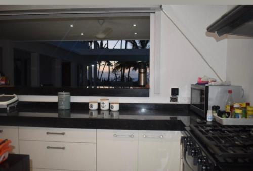 uma cozinha com armários brancos e um balcão preto em Villa Brise de Mer em Las Terrenas