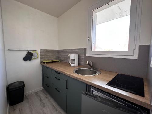 une petite cuisine avec un évier et une fenêtre dans l'établissement Appartement rénové avec véranda, proche plage et commerces - Notre-Dame-de-Monts - FR-1-540-259, à Notre-Dame-de-Monts