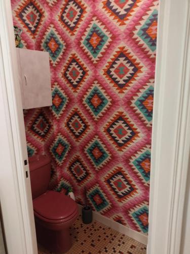een badkamer met een rood toilet en een muur met patronen bij Charmant appartement au bord du Thiou - Annecy in Annecy