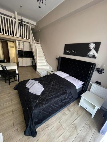 ミエンジズドロイェにあるApart Promenada Gwiazdのベッドルーム1室(黒いベッド1台、階段付)