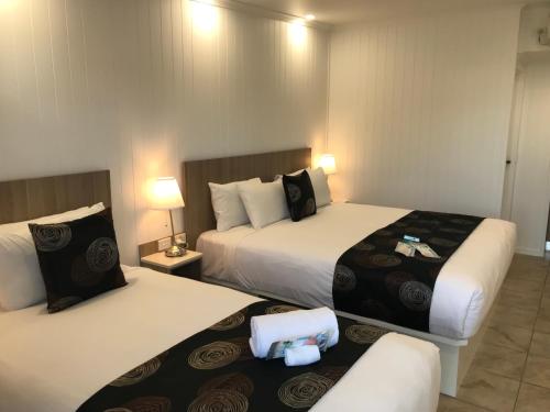 a hotel room with two beds and two lamps at Room Motel Kingaroy East in Kingaroy