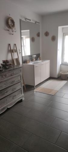 uma casa de banho com um lavatório, uma cómoda e um espelho. em Lilas em Giromagny