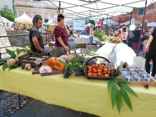 dwóch mężczyzn stojących obok stołu z owocami i warzywami w obiekcie Agriturismo La Fogona w mieście Carrodano Superiore