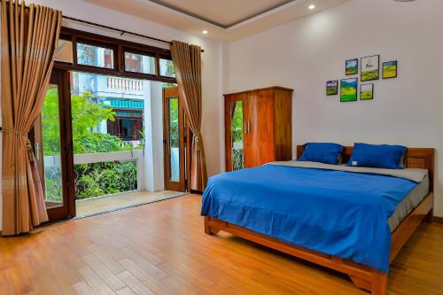 a bedroom with a blue bed and a large window at Simple House Near My Khe Beach and Night Street in Da Nang