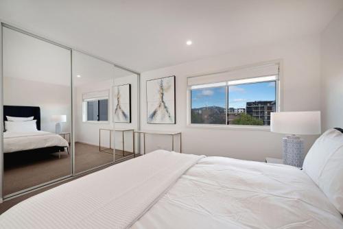 ein weißes Schlafzimmer mit einem Bett und einem Fenster in der Unterkunft The Menzies Suite in Canberra