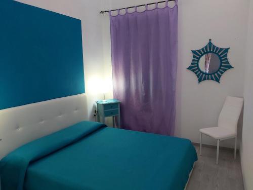 ein Schlafzimmer mit einem blauen Bett und einem Stuhl in der Unterkunft Casa Mela in Castelsardo