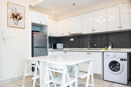 a kitchen with white cabinets and a white table and chairs at Stay @ Almas Puteri Harbour in Nusajaya