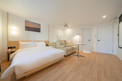 a large white bedroom with a bed and a chair at Aank Hotel Cheonan Station 1st in Cheonan