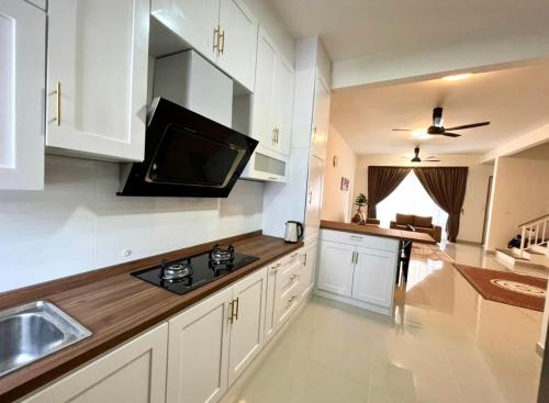 a kitchen with white cabinets and a television on the wall at Homestay Ika KLIA @ Enstek in Kampong Chinchang