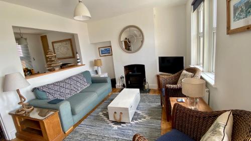 a living room with a blue couch and chairs at Cozy coastguard cottage with sea views in East Cowes