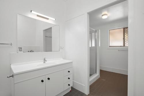 un bagno bianco con lavandino e specchio di Cypress Cottage 26 Cypress Street Evans Head a Evans Head