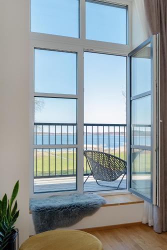 a room with a window with a chair on a balcony at Tamula Lake View Apartment in Võru