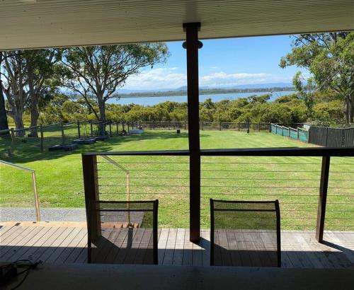 a view of a field from a porch with two benches at Ranges Over the Bay in Culburra Beach
