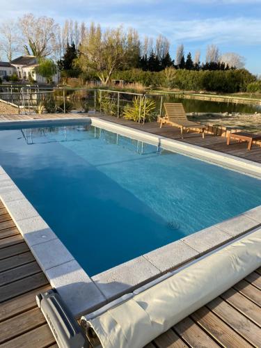 une grande piscine d'eau bleue sur une terrasse en bois dans l'établissement LA ROULOTTE DE MOUCHOU, à Saintes-Maries-de-la-Mer