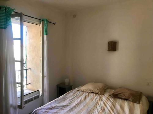sypialnia z łóżkiem i oknem w obiekcie Appartement face aux Arènes w mieście Arles