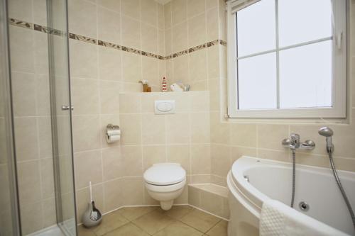 a bathroom with a toilet and a tub and a window at idyllisches Ferienhaus mit eigener Sauna, Kamin und Terrasse - Haus Kranich in Vieregge