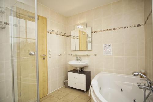 a bathroom with a tub and a sink and a shower at idyllisches Ferienhaus mit eigener Sauna, Kamin und Terrasse - Haus Boddenblick in Vieregge